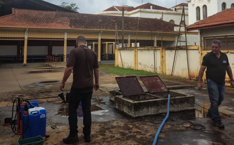 Dois profissionais em pátio externo, junto a um reservatório de concreto aberto