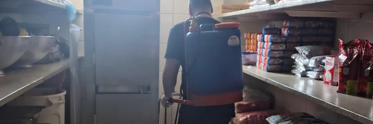 Profissional com bomba costal em corredor de estoque com prateleiras de alimentos