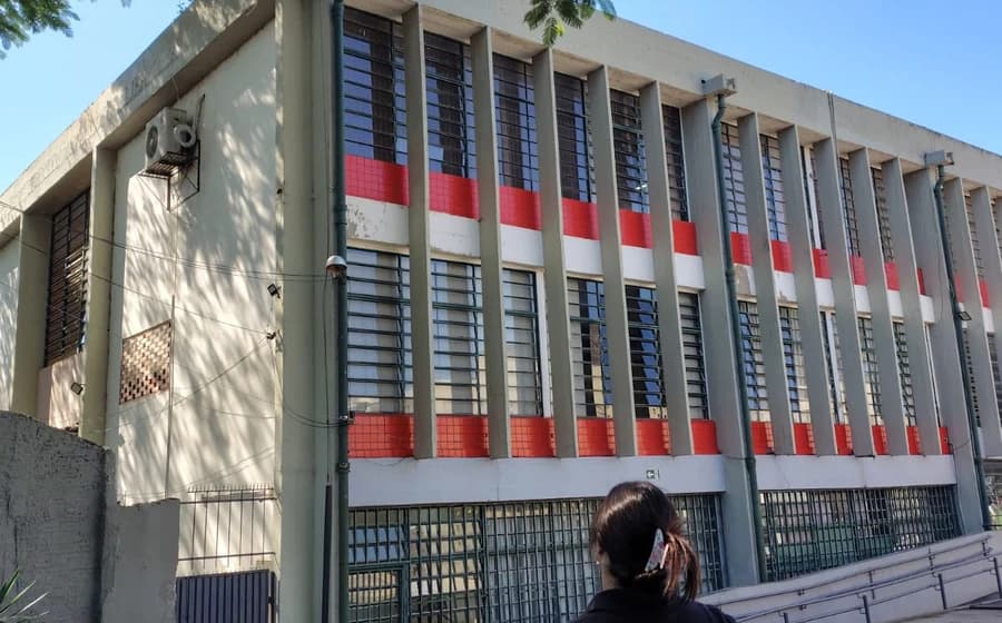 Profissional com uniforme da JC&C diante da fachada de um prédio institucional