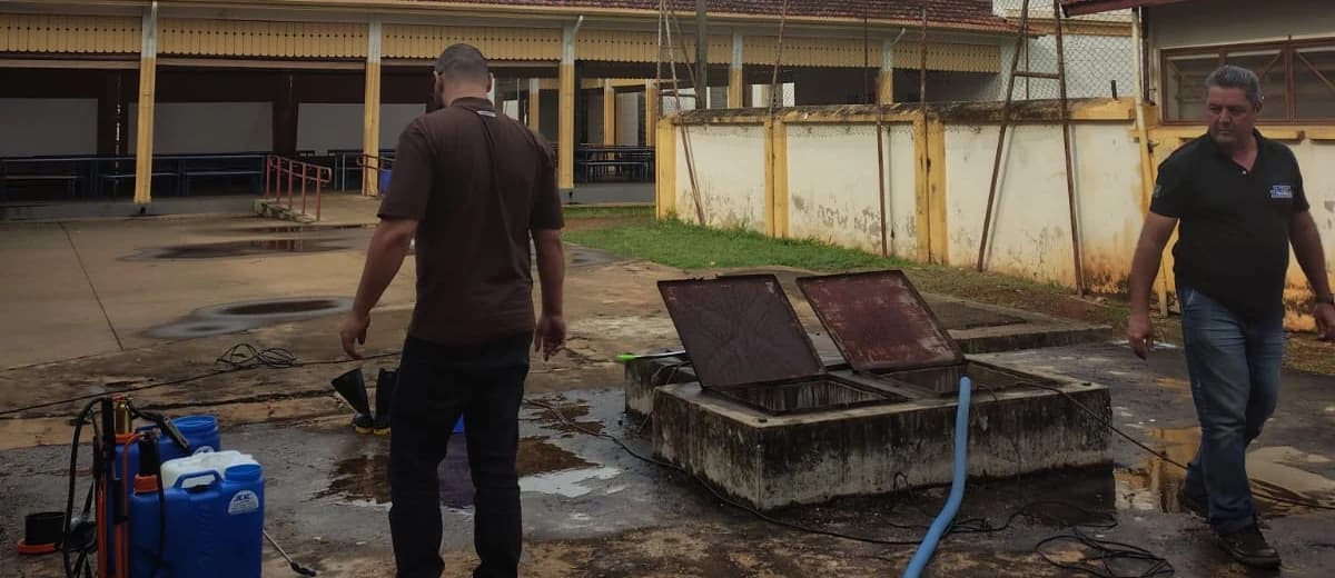 Dois profissionais em pátio externo, junto a um reservatório de concreto aberto